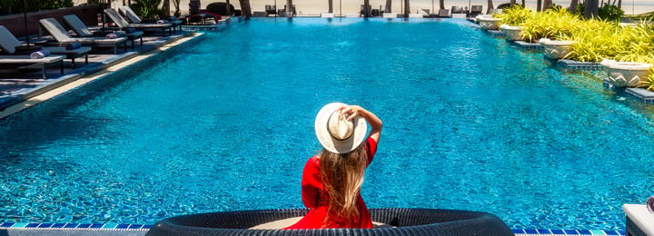 Women-with-Hat-Sitting-by-Resort-Swimming-Pool